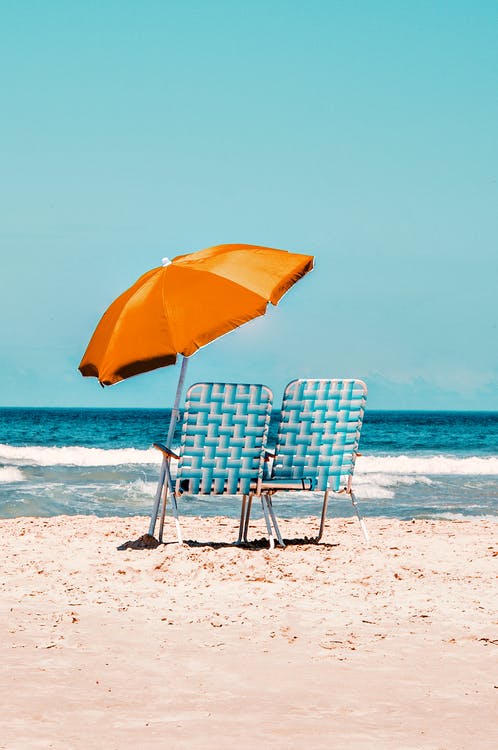 beach picture with two chairs and an umbrella