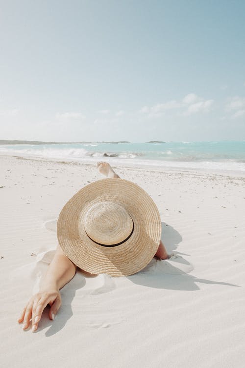woman in hat lying on beach