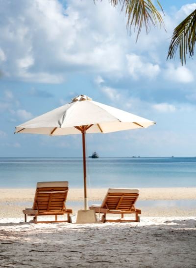 two wooden lounge chairs under a beach umbrella