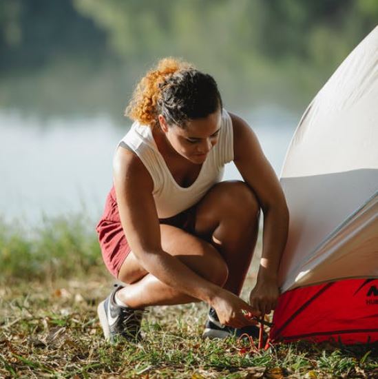 a woman securing her tent with an anchor