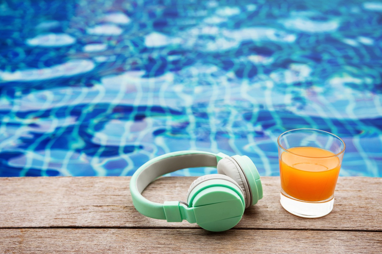 a headphone and glass of juice by the side of the pool